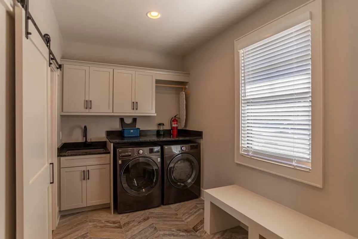 A tidy laundry room with a washer and dryer, countertop workspace, and ample storage cabinets—providing practical convenience for household routines and post-adventure cleanups.